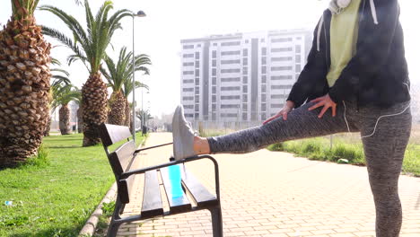 woman in sportswear and protective mask doing stretching on bench