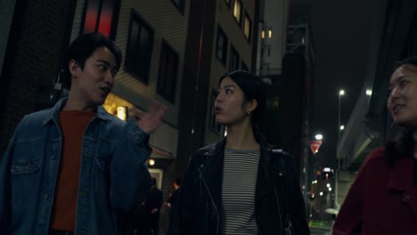 group of friends walking down a city street at night