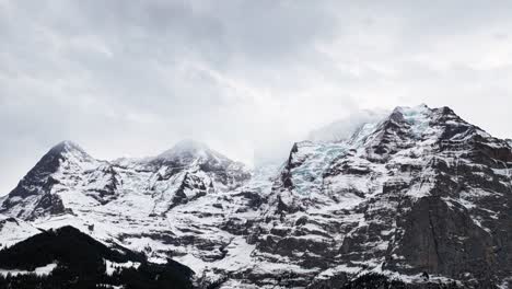 clouds move above scenic switzerland mountain range with snow and ice