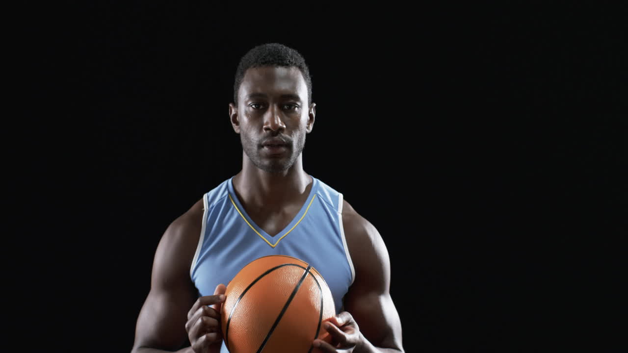 African American man holding a basketball on a black background