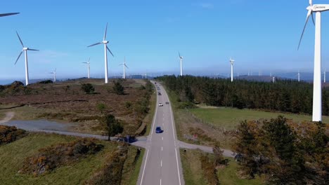 combustion cars circulating through a large wind farm of wind turbines moving their blades with the wind