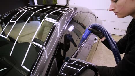 professional car washer in black gloves wipes the car after washing and lining ceramics. concepts of: professional work, various washing tools, cleaning to shine.