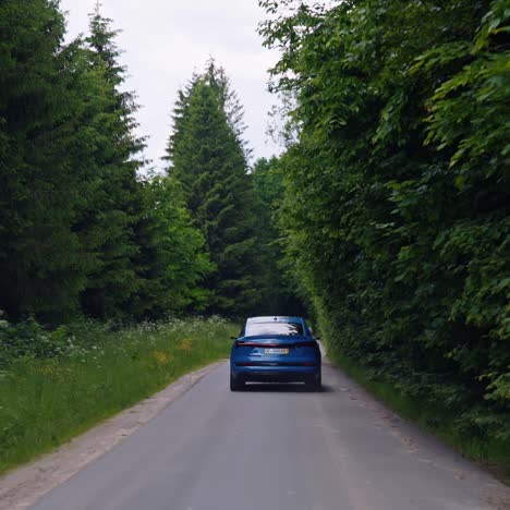 electric suv car driving among green nature. new audi e-tron blue color with highlights on. sportive car model moving on a road in the forest. save environment