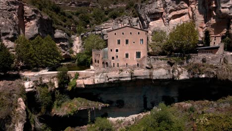 vistas aéreas de um espaço natural em um vale verde com um edifício e algumas cachoeiras na catalunha