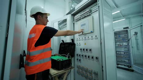 electrical engineer working check the electric current voltage and overload at front of load center cabinet or consumer unit for maintenance in main power distribution system room.