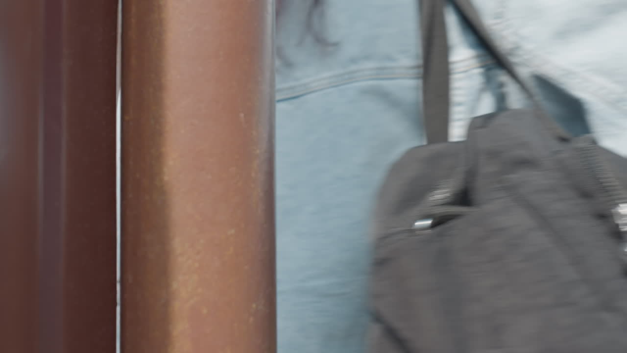 Close up of brown iron gate partially opened as women walk through entrance into home on bright sunny day, wooden fence visible in background with green trees out of focus in residential setting