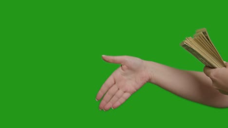 una mano masculina extiende un gran paquete de dinero a una mano femenina, transacción, apretón de manos, pantalla verde
