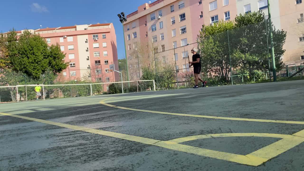 Entrenando o enseñando a jugar tenis en una cancha al aire libre
