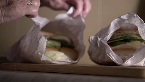 dama de edad avanzada con sándwiches recién preparados en bolsas de tiro medio