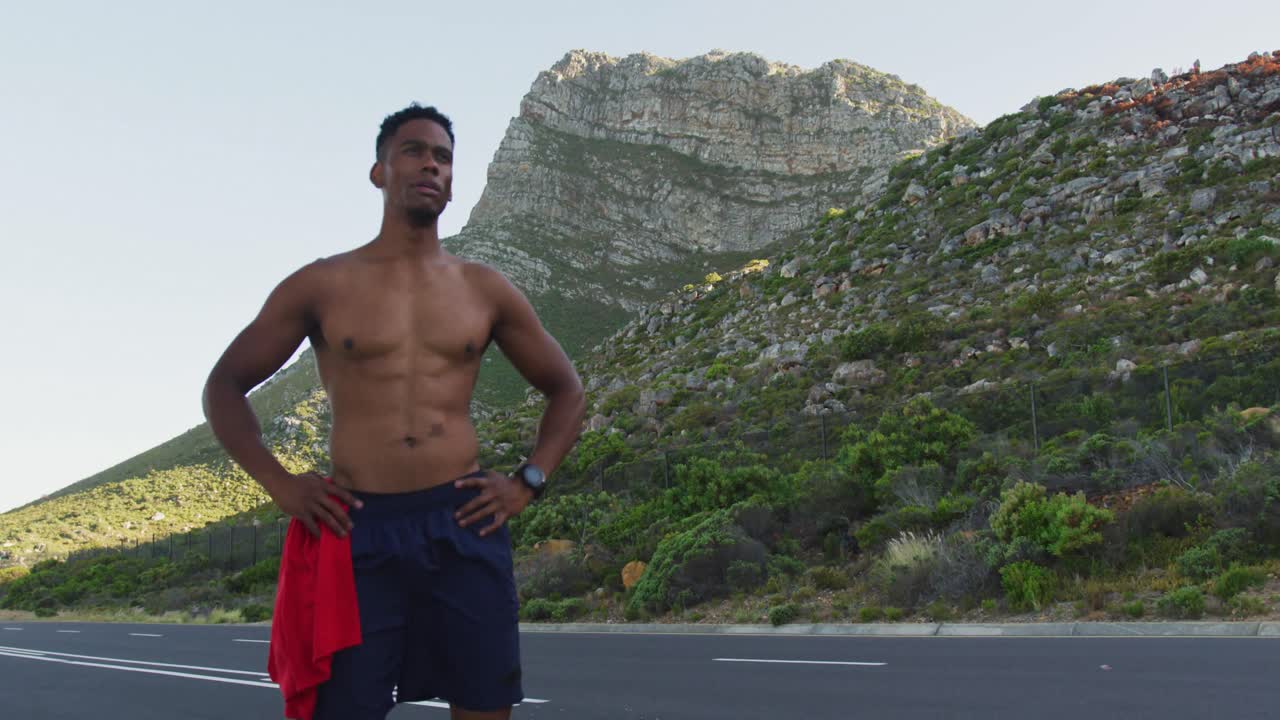 African american man standing and flexing his muscles on a coastal road