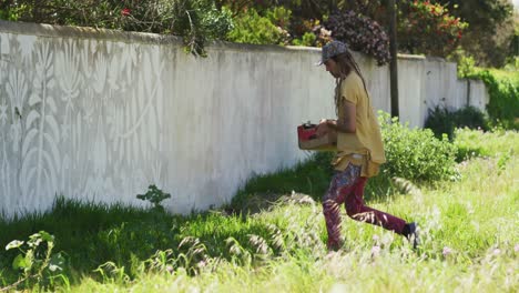 Video-of-caucasian-male-artist-with-dreadlocks-carrying-paints-to-mural-on-wall