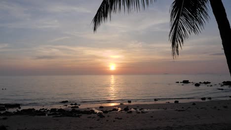 Puesta-De-Sol-En-Una-Playa-De-Arena-Con-Palmeras-En-Tailandia---Cámara-Ultra-Lenta-Inclinándose-Hacia-Arriba-Y-Luego-Estática