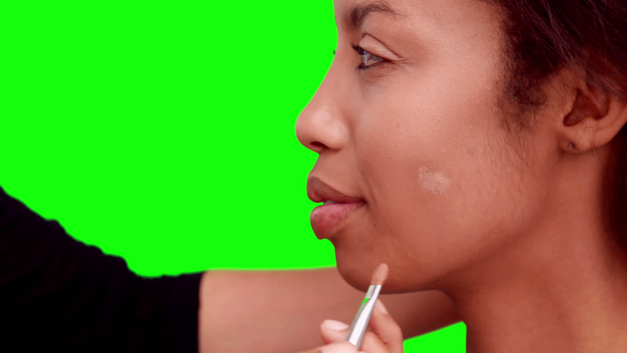 artista de maquillaje poniendo fundación en la cara de los modelos