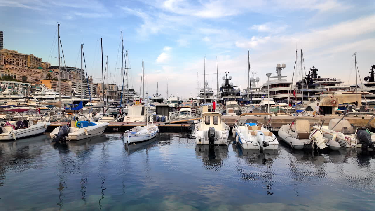 Vista di barche bianche ormeggiate nel porto turistico di Monaco con lo skyline della città sullo sfondo