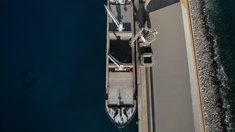 aerial shot from above and revealing one of the ships that transport the merchandise and the cranes that load the cement