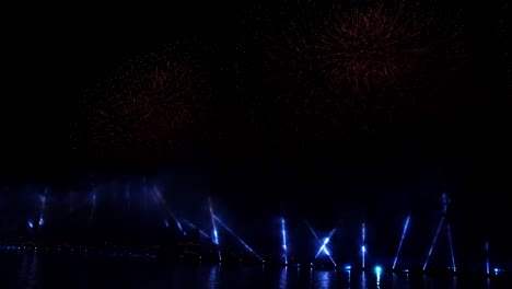 fuegos artificiales coloridos festivos e iluminación en el cielo oscuro con un hermoso reflejo en el agua. velas escarlata de vacaciones