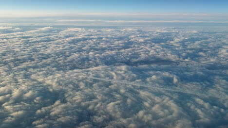 vista increíble desde la cabina de un avión que vuela alto por encima de las nubes dejando un largo rastro de aire de vapor de condensación blanco en el cielo azul