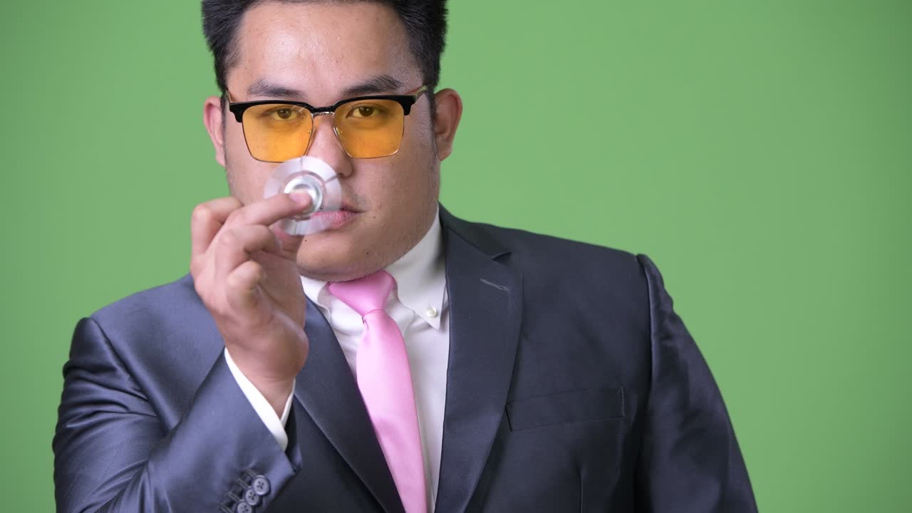 초록색 배경에 젊은 잘생긴 과체중 아시아 사업가