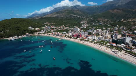 Las-Aguas-Color-Turquesa-Esmeralda-De-La-Bahía-Del-Mar-Jónico-En-La-Tranquila-Ciudad-Costera-De-Himara-Dan-La-Bienvenida-A-Los-Turistas-Para-Las-Vacaciones-De-Verano