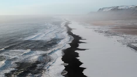 Toma-Cinematográfica-De-Un-Dron-De-Una-Playa-De-Basalto-Negro-Con-El-Océano-Atlántico-En-La-Isla-De-Islandia