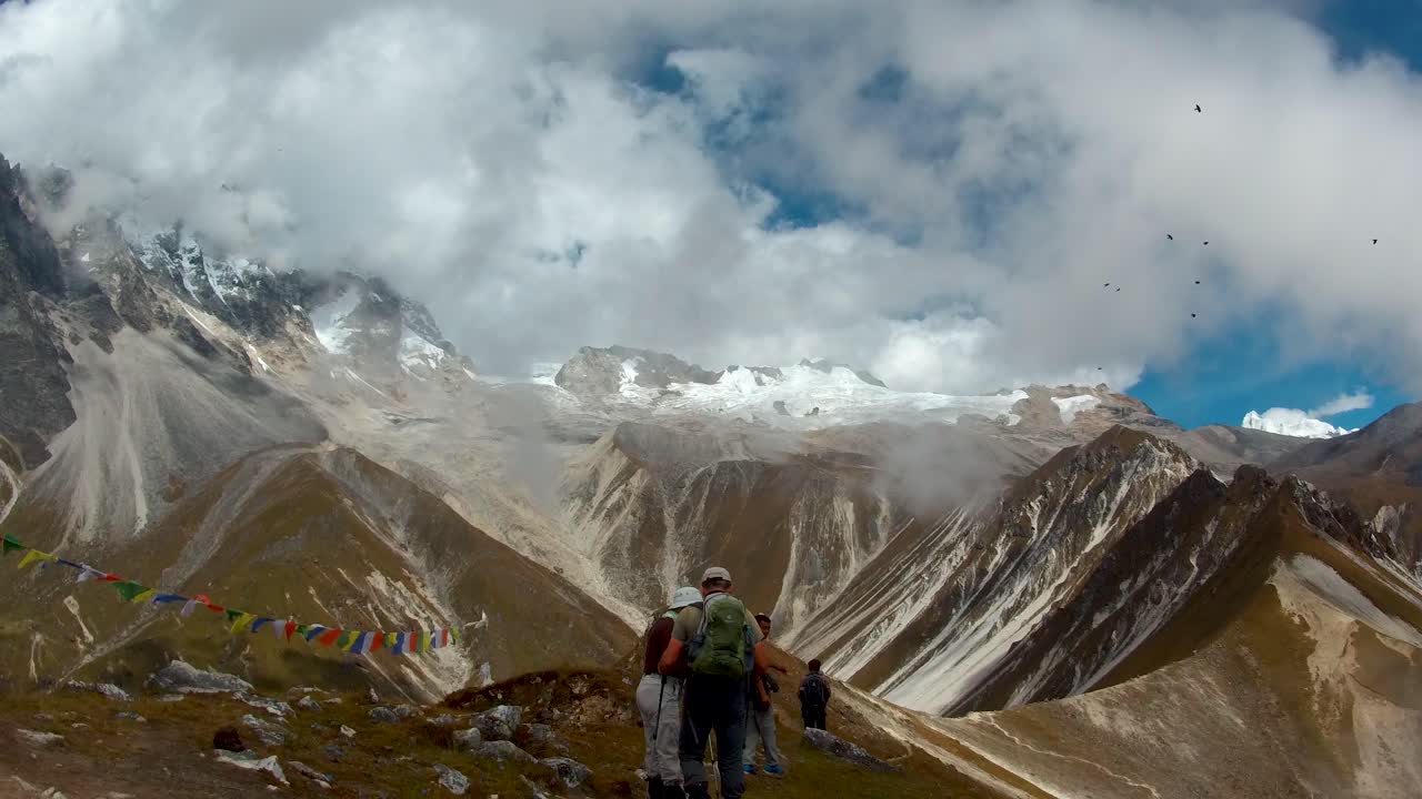 Unidentified fellow trekkers wave goodbye and start hiking downhill towards the basecamp. Surreal Himalaya Serene in the backdrop. Langtang valley of Nepal.