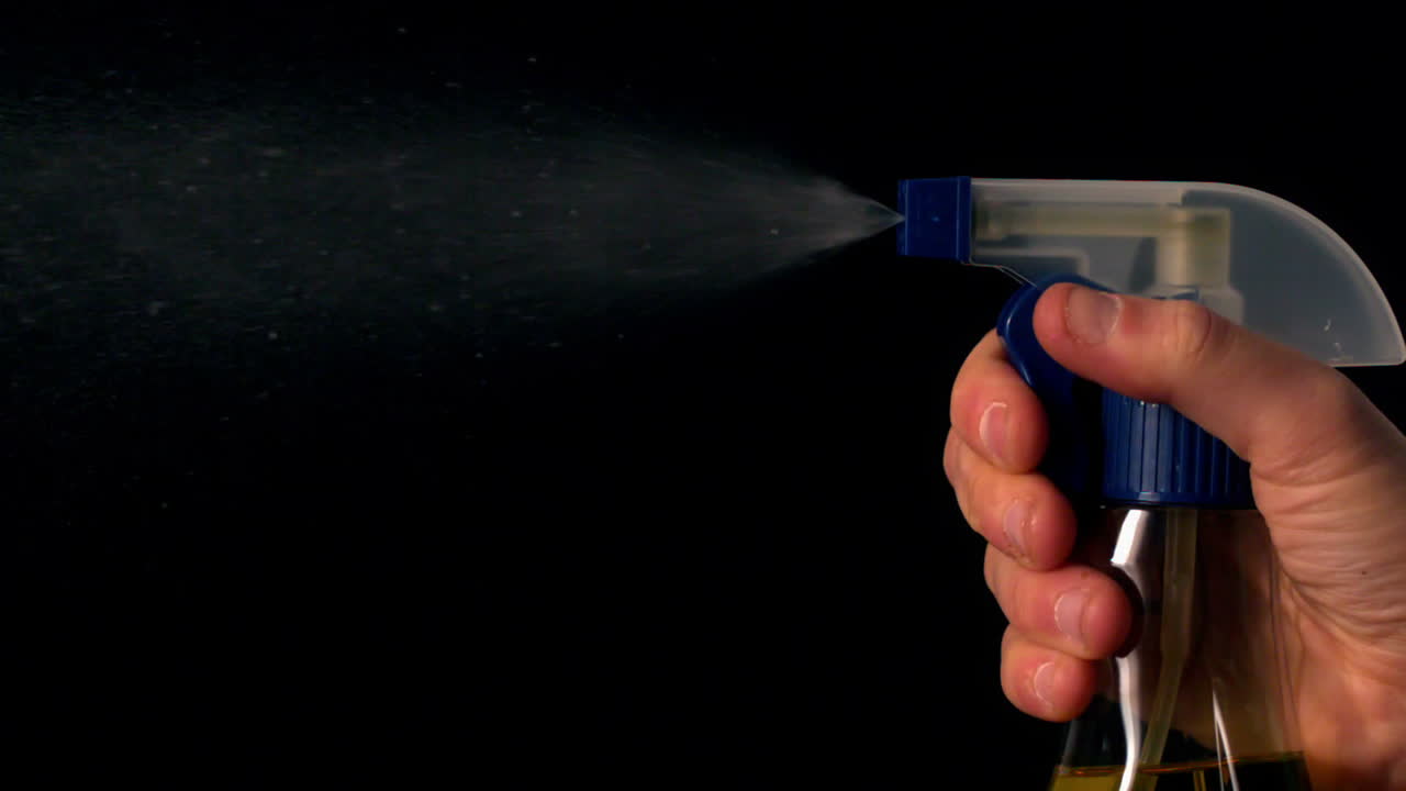 mujer rociando limpiador de una botella de spray