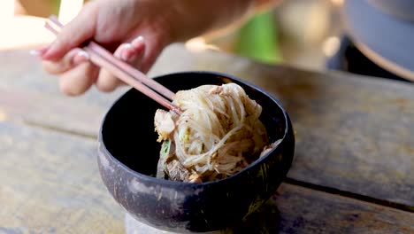 chopsticks lifting noodles from a bowl