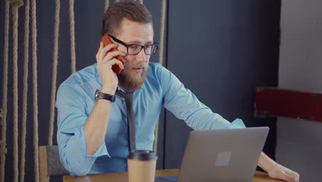 hombre de negocios hablando por teléfono y trabajando en una computadora portátil en un café