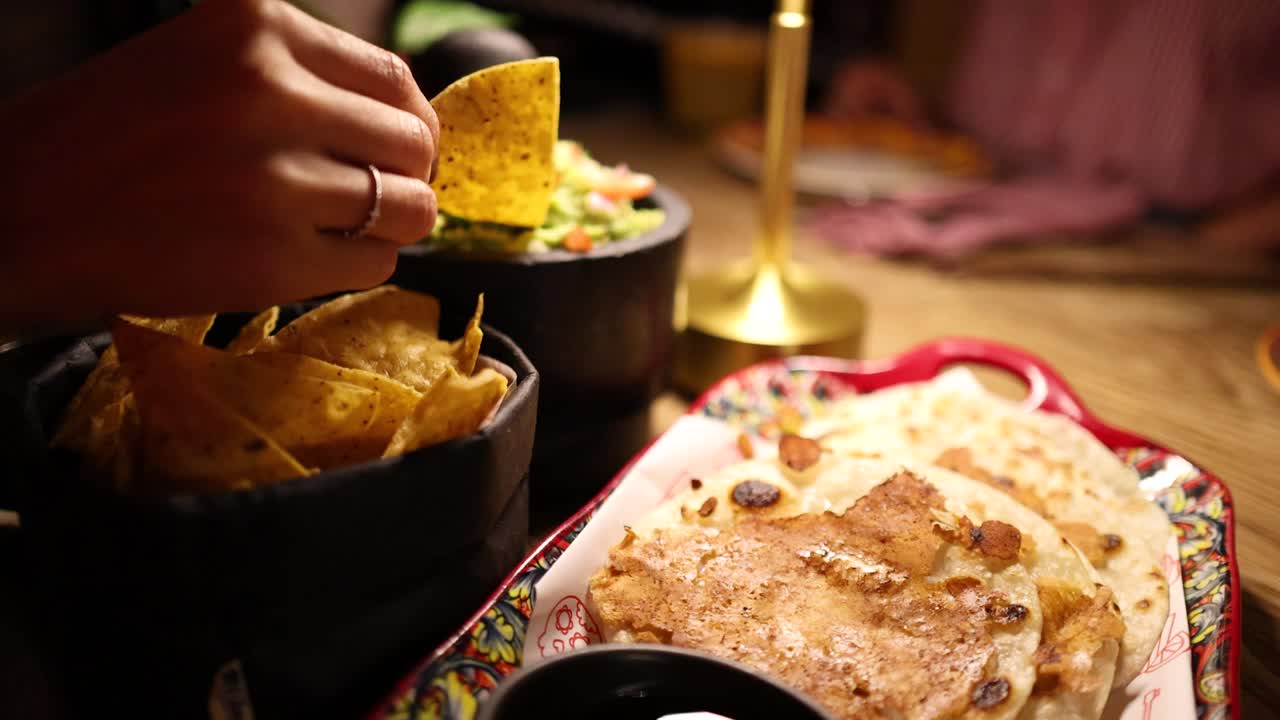 A cozy dining scene with nachos, guacamole, and tlayudas under warm lighting in a Bangkok restaurant