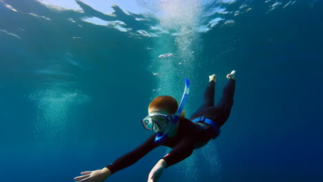 person snorkeling underwater in clear blue water