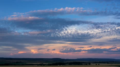 calmante lapso de tiempo del cielo rosa del atardecer que se convierte en cielo nocturno con nubes que se mueven rápidamente sobre las montañas y el paisaje de la granja