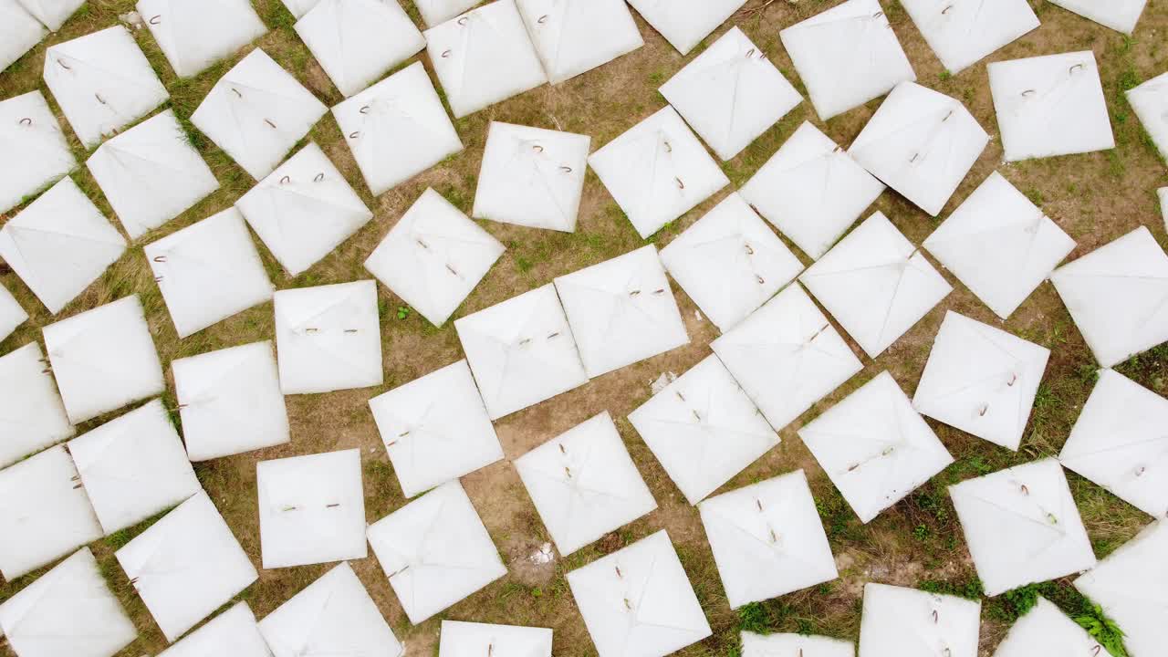 Aerial View of Numerous White Square Objects Arranged on a Grassy Field