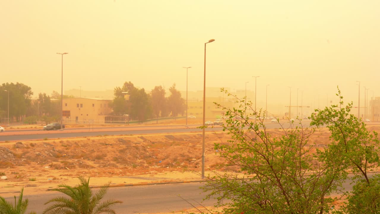 Urban street and traffic under thick desert sandstorm, showcasing severe weather and atmospheric haze in a dry environment.