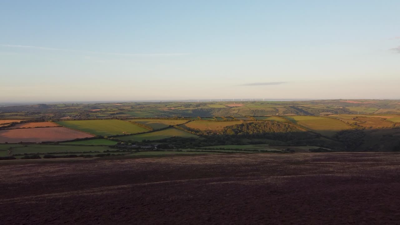 Fast Rising Aerial Drone with Beautiful Purple Heather Rolling Fields and Wind Turbine Farm in Distance Exmoor Devon UK