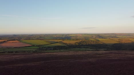 Fast-Rising-Aerial-Drone-with-Beautiful-Purple-Heather-Rolling-Fields-and-Wind-Turbine-Farm-in-Distance-Exmoor-Devon-UK