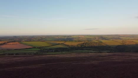 dron aéreo de rápido crecimiento con hermosos campos ondulados de brezo púrpura y granja de turbinas eólicas en la distancia exmoor devon uk