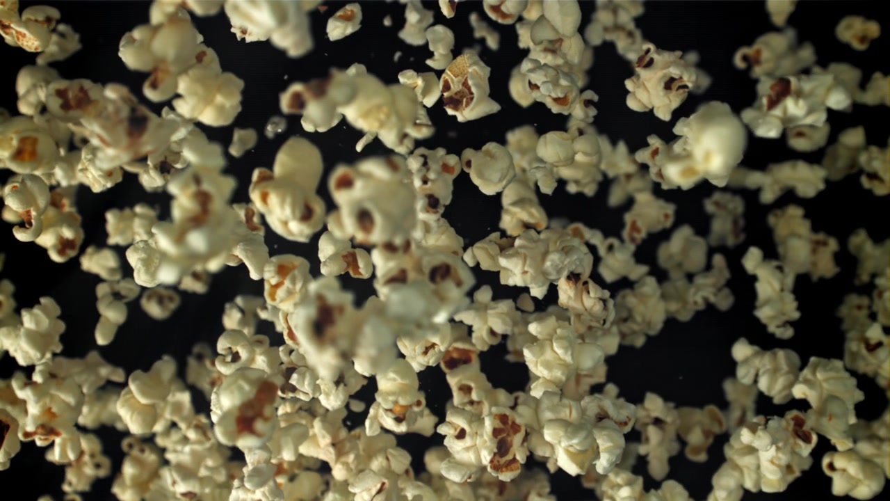 Chicchi di popcorn che cadono al rallentatore su uno sfondo nero