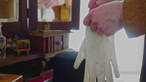 man putting on white gloves in a vintage dressing room