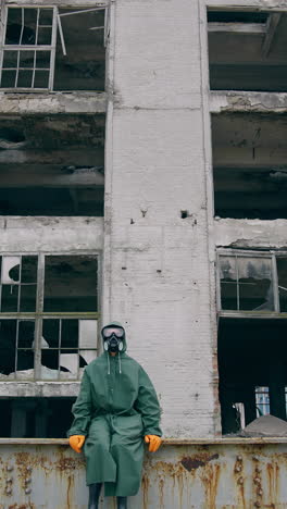 survivor after nuclear chemical incident. man in gas mask near abandoned destroyed building