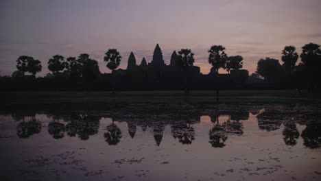 dawn breaks over angkor wat with a vibrant sky reflecting in the water, serene and majestic, timelapse