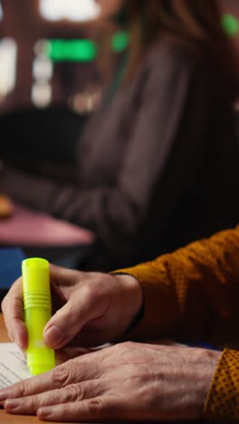 vertical video elderly student using highlighter pen to memorize lesson papers