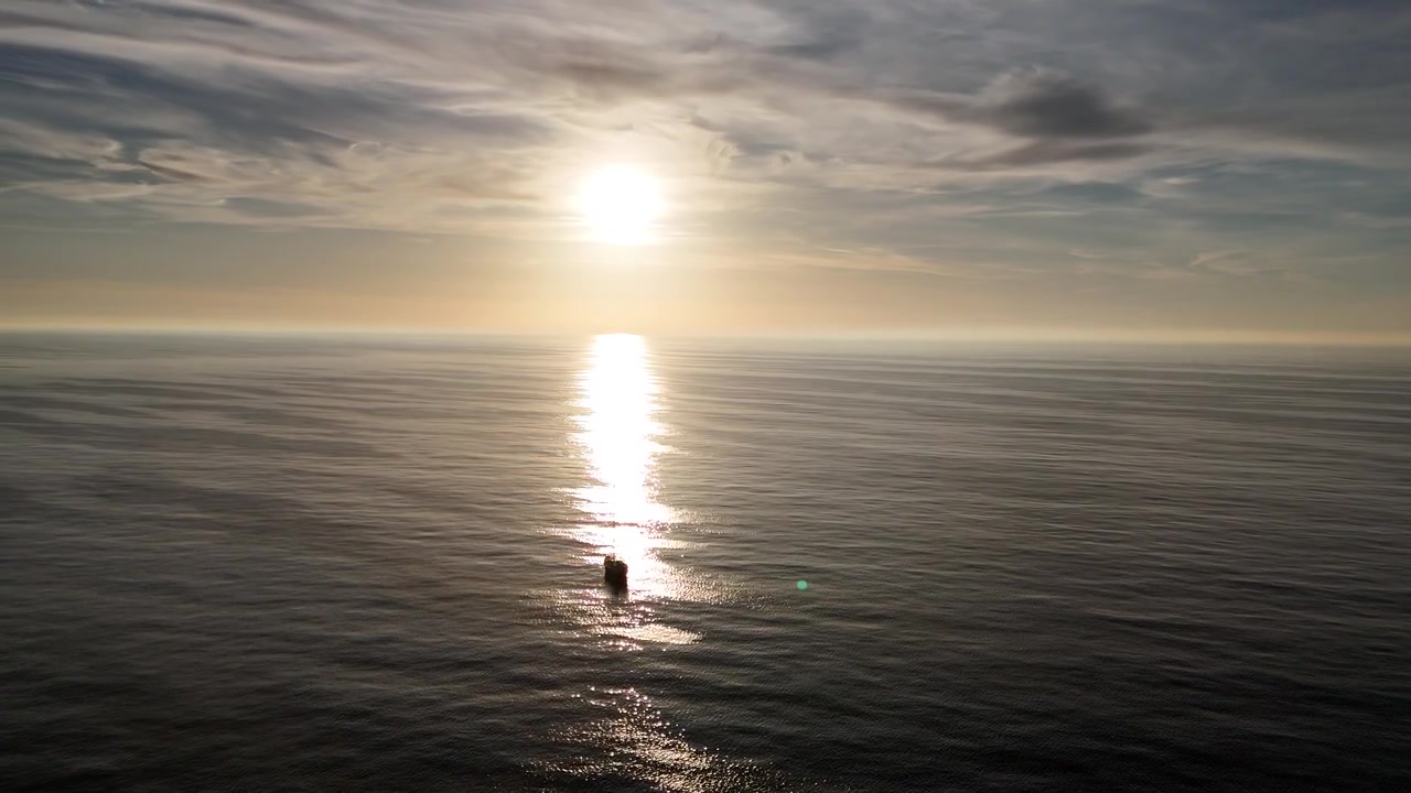 Slow circular drone move framing sailboat against sunlight.