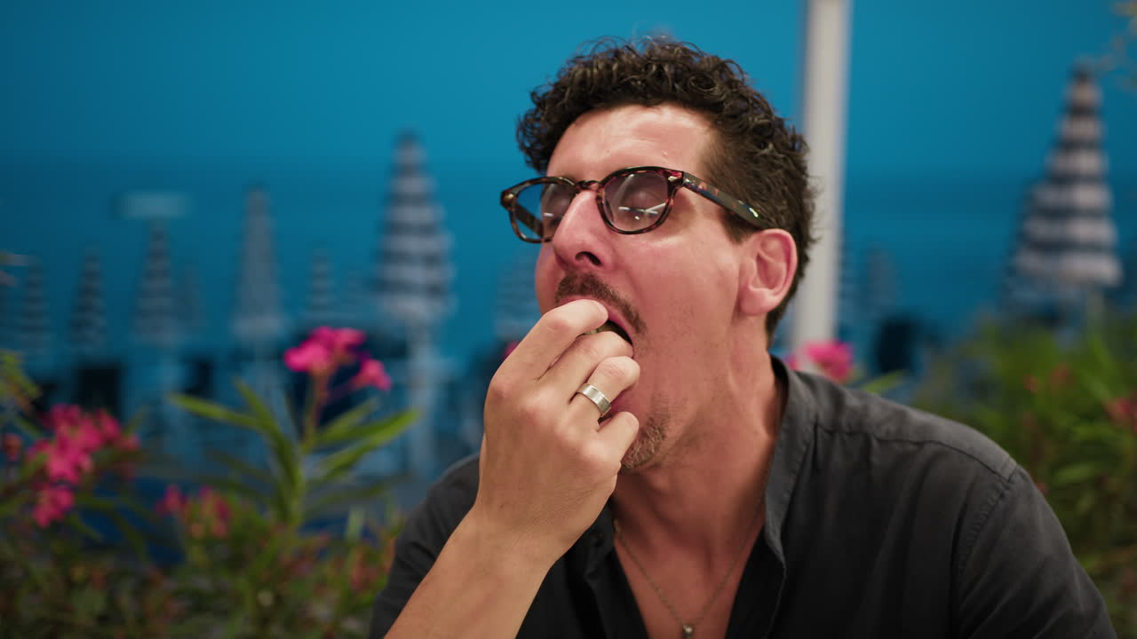 Man Eating A Burger And Smiling At The Resort With Sea Background
