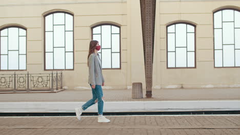 young woman in a face mask walking on a train station platform