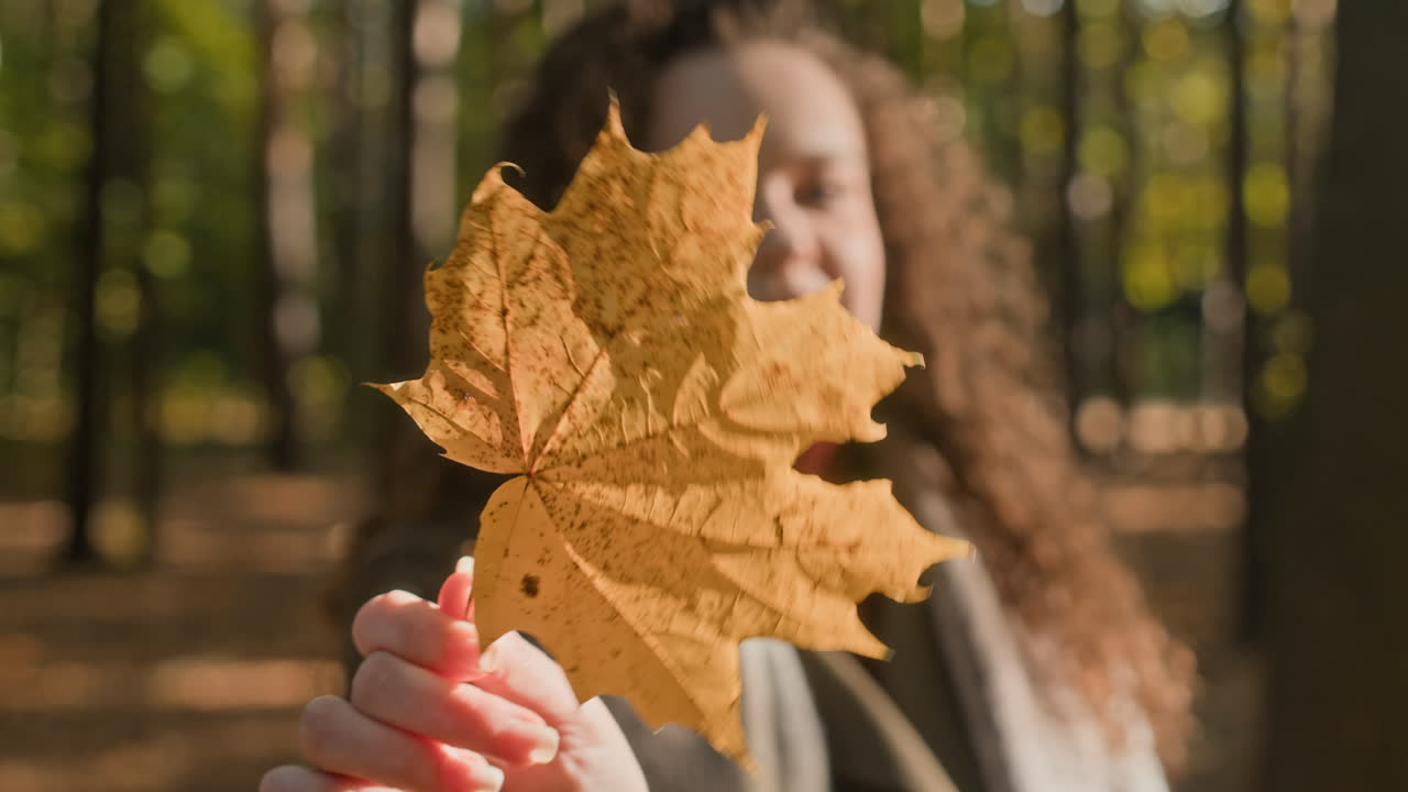 Woman with autumn leaf in forest