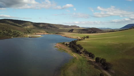 drone pan up over rural dam and hillside in tasmania, australia