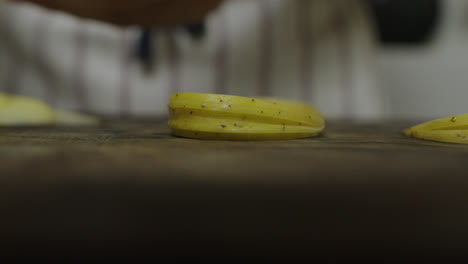 Chef-places-stacked-potato-slices-onto-wooden-cut-board