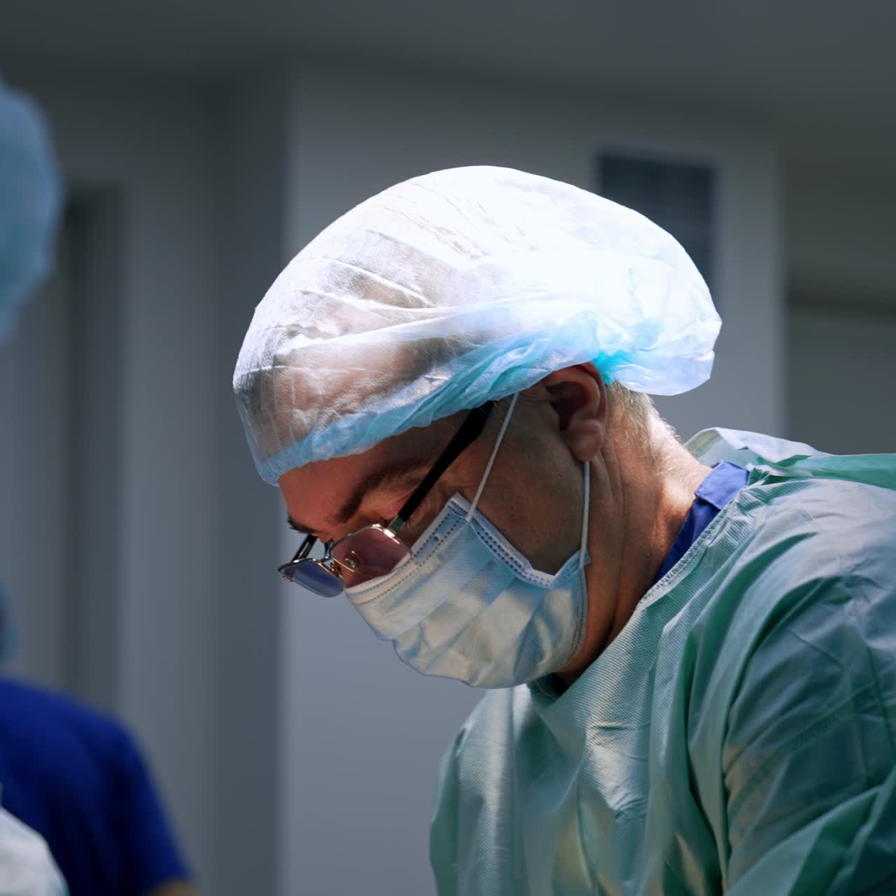 Un gruppo di medici esegue un intervento chirurgico. I medici si passano gli strumenti di metallo e sono tutti chini, concentrati sul lavoro.