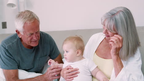 Grandparents-Lying-In-Bed-At-Home-Looking-After-Baby-Grandson