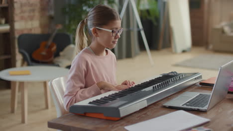 young girl learning to play keyboard at home